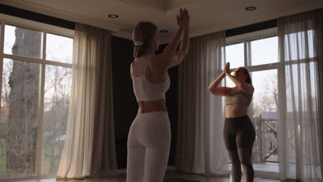 Young-Caucasian-sporty-people-practicing-yoga-lesson-with-instructor.-Caucasian-group-of-women-exercising-healthy-lifestyle-in-fitness-studio.-Sport-activity-gymnastics-class.-Slow-motion.